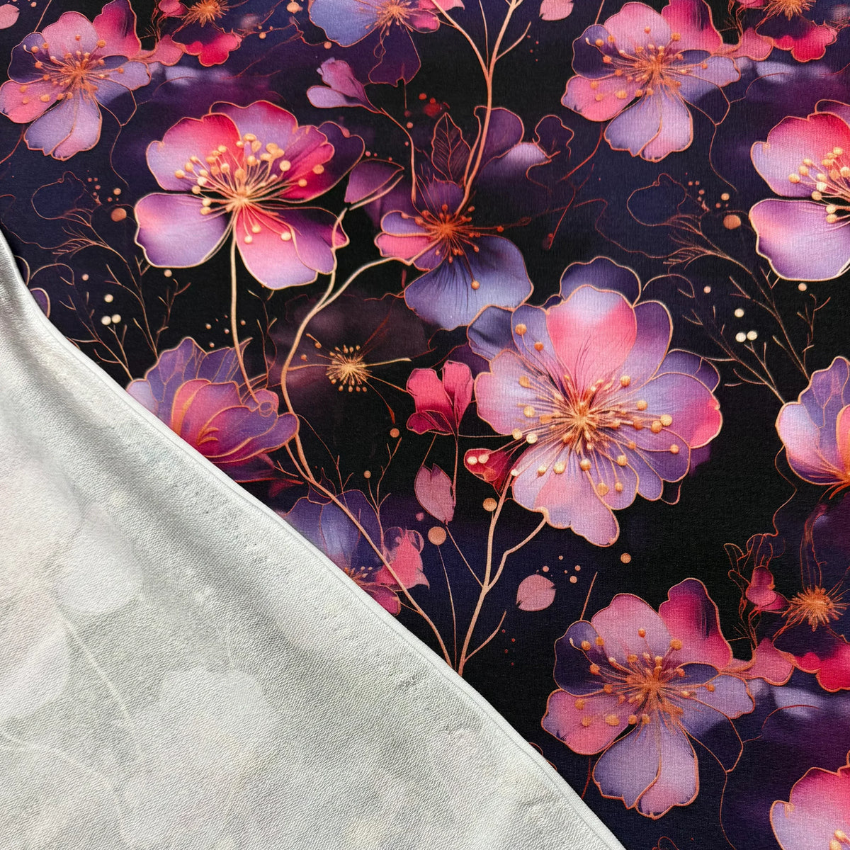 Nature's Fabrics purple pink floral print fabric with dark background, showcasing vibrant blossoms and delicate stems