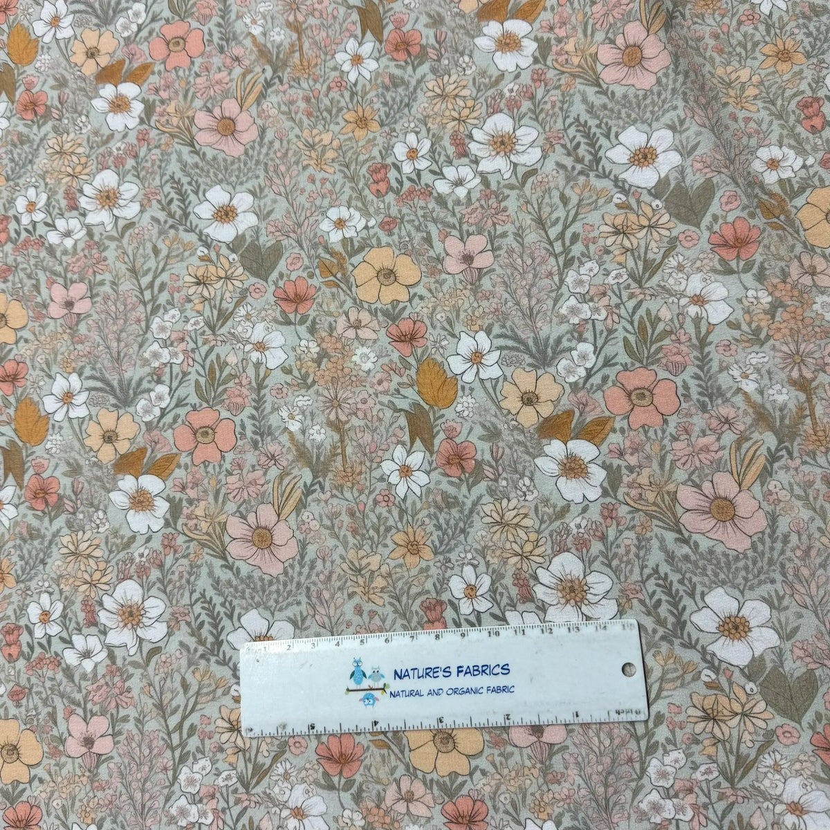 Nature's Fabrics floral print organic cotton fabric with pink, white, and yellow flowers, ruler for scale