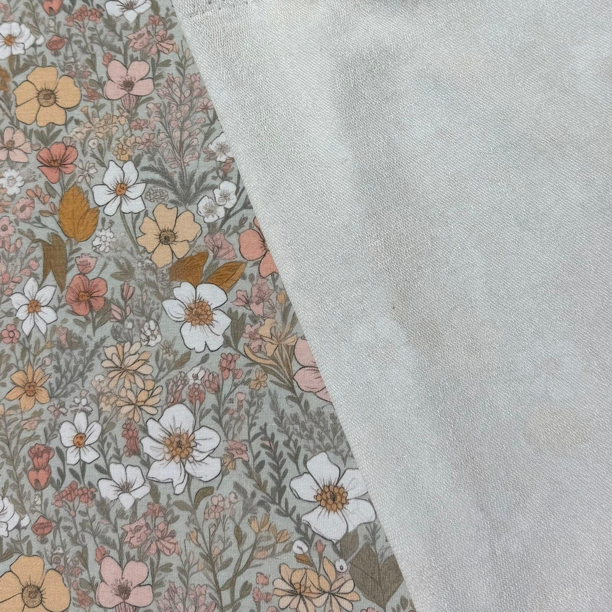 Floral print natural fabric by Nature's Fabrics with a plain light grey reverse side.
