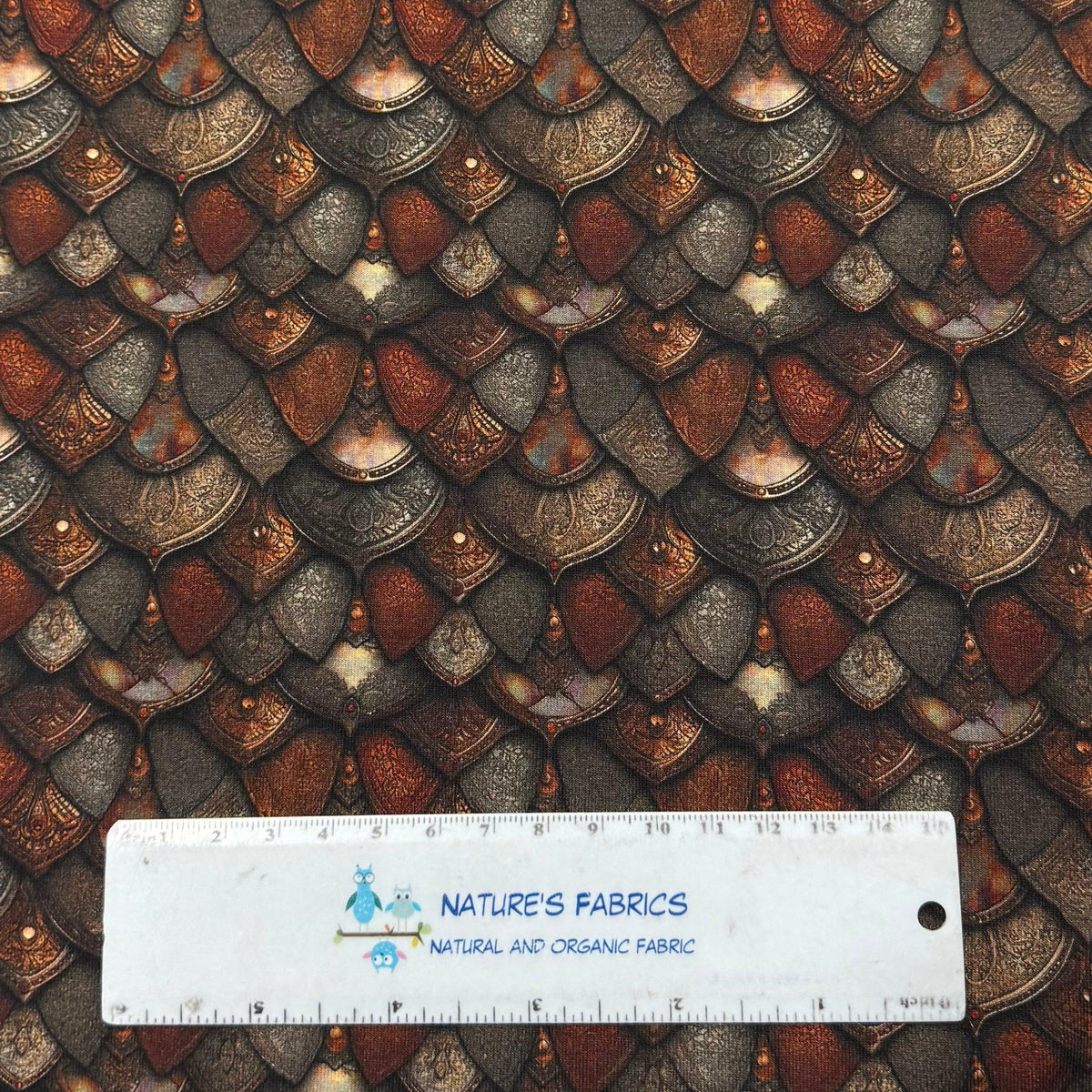 Dragon scale print fabric by Nature's Fabrics, featuring metallic bronze and gray scales with ruler for scale