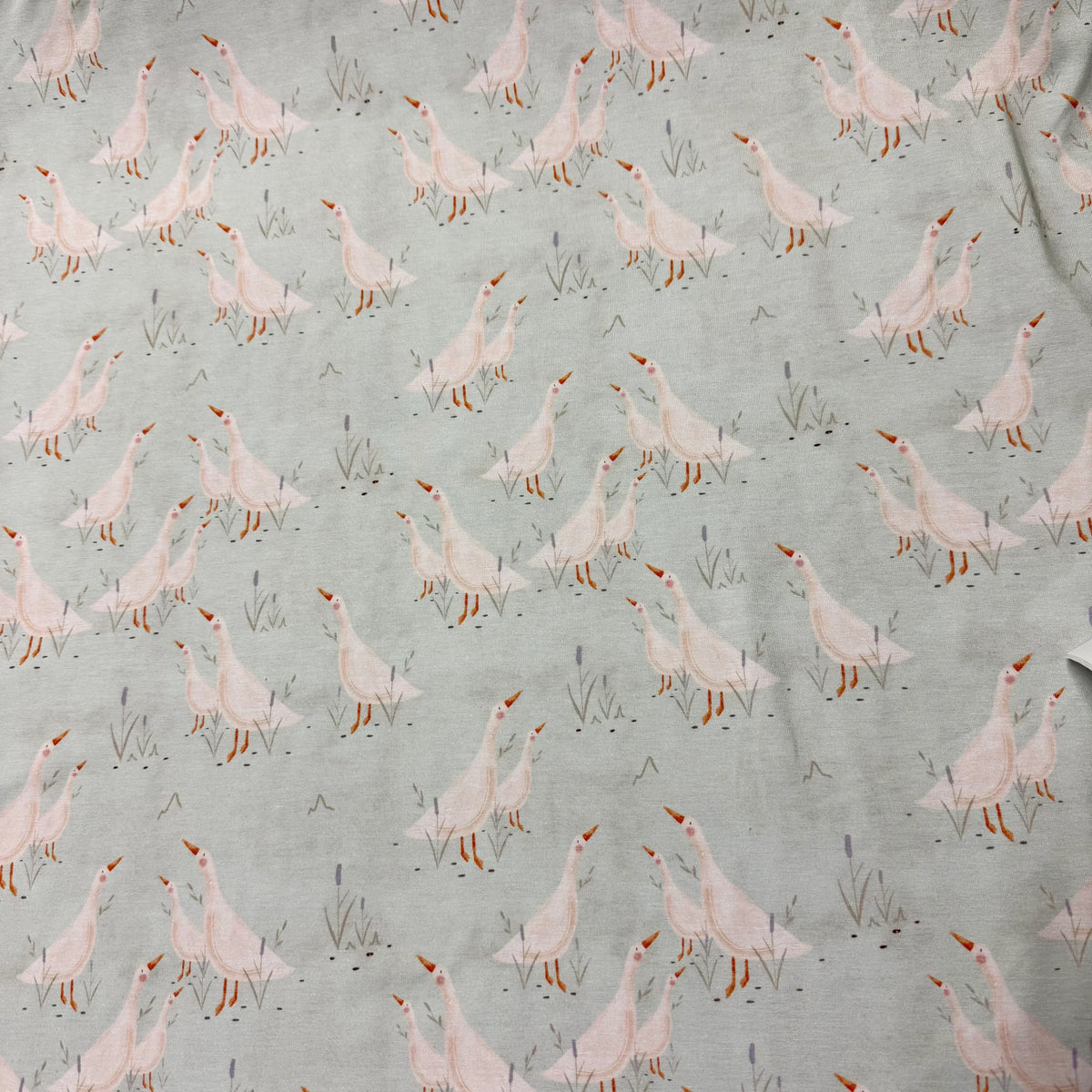 Nature's Fabrics light grey organic cotton fabric with a pink goose print pattern.