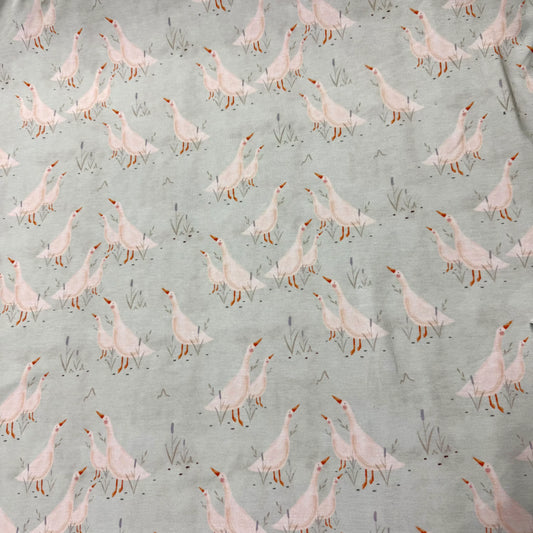 Nature's Fabrics light grey fabric featuring a repeating pattern of pink geese and grass.