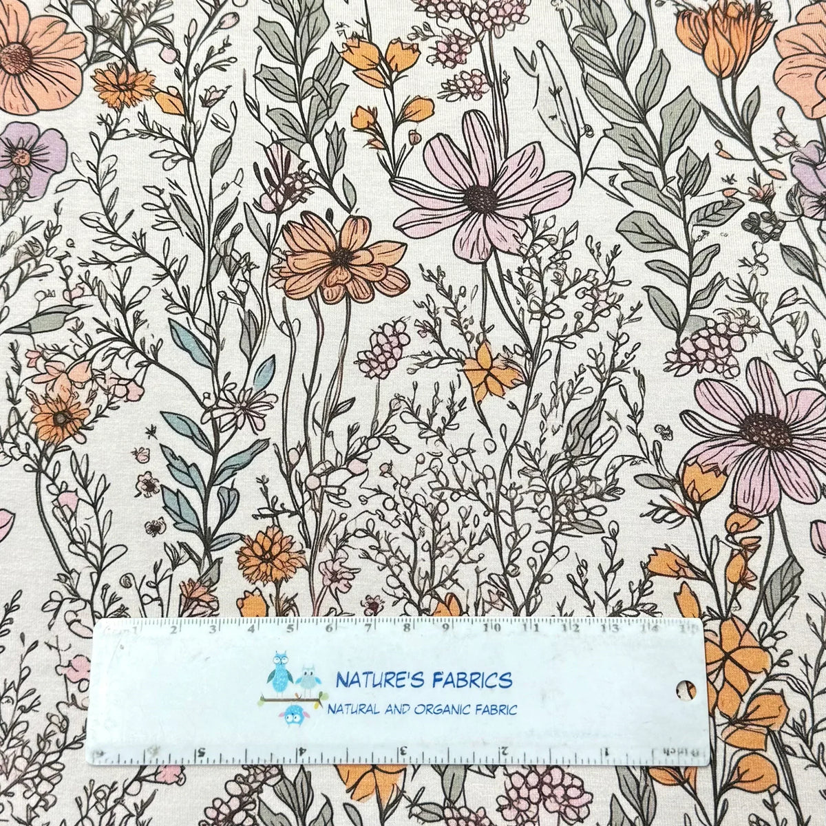 Nature's Fabrics floral print fabric with pink, orange, and purple flowers on light background, ruler for scale