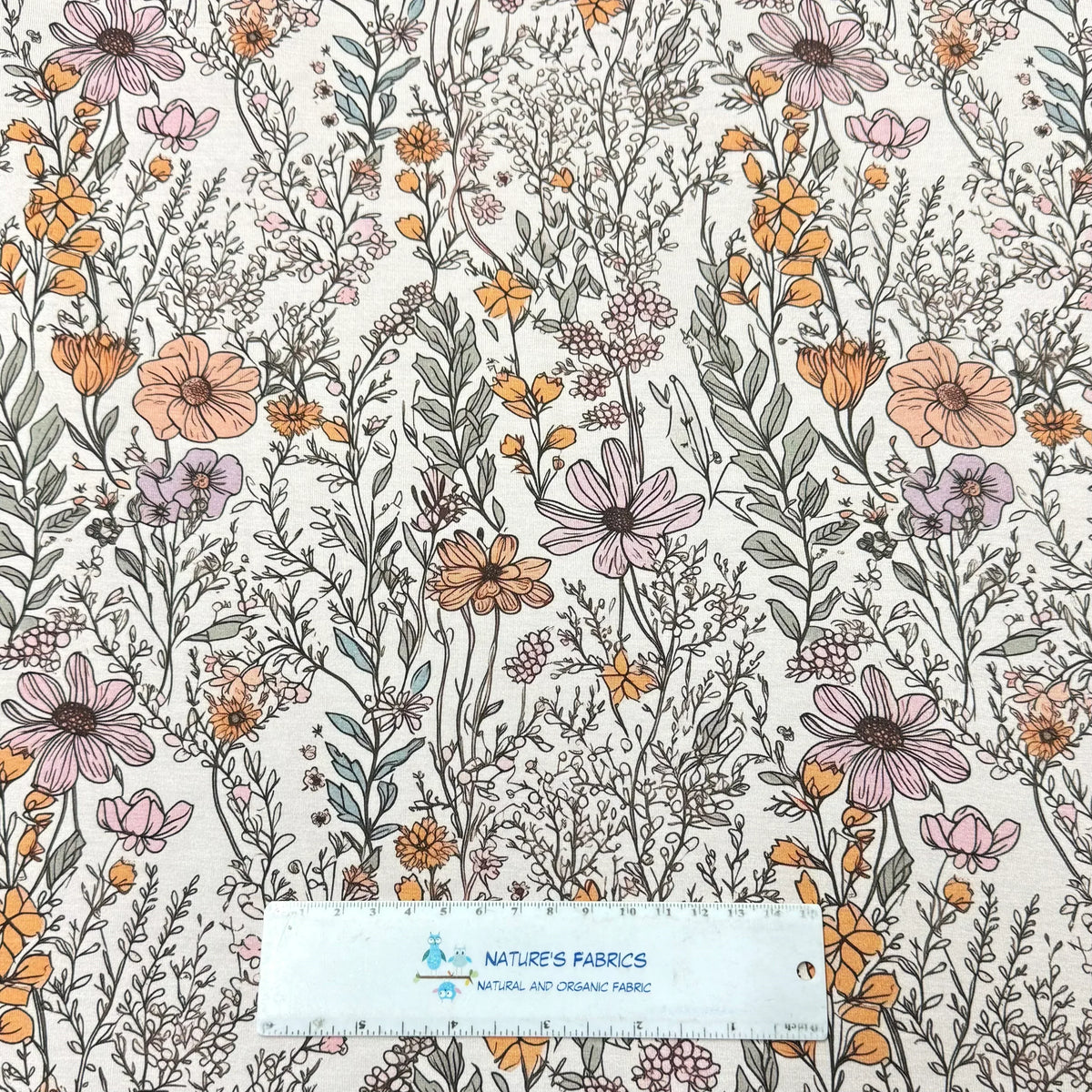 Nature's Fabrics organic cotton fabric with a muted orange and purple floral pattern.