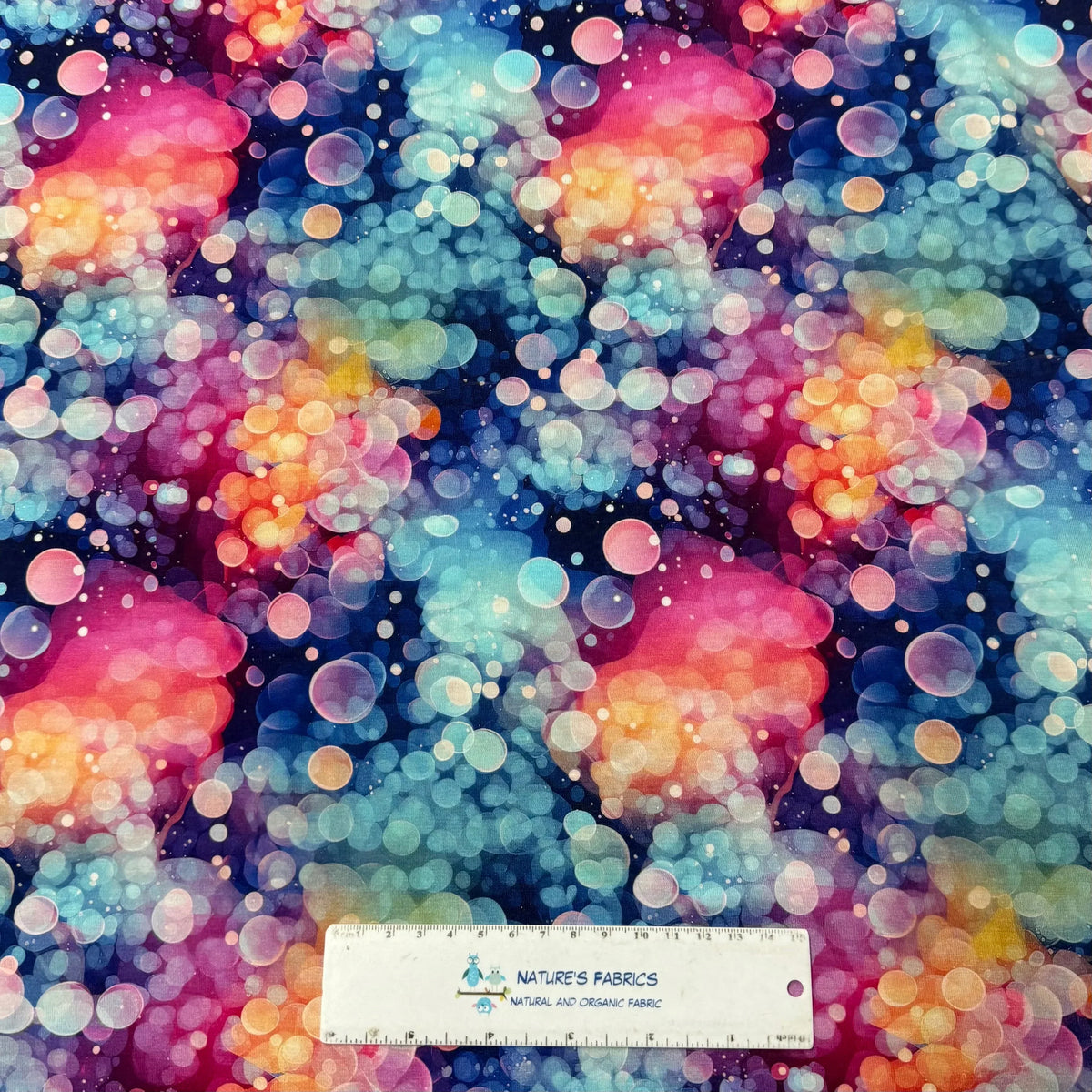 Nature's Fabrics colorful bokeh print fabric with a measuring ruler for scale.