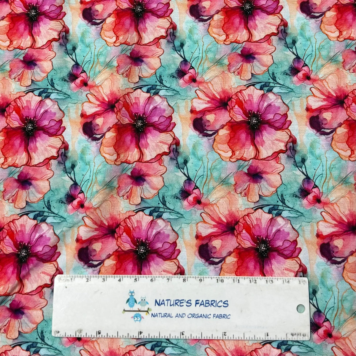 Nature's Fabrics watercolor poppy print organic cotton fabric with ruler for scale, vibrant pink and teal floral design