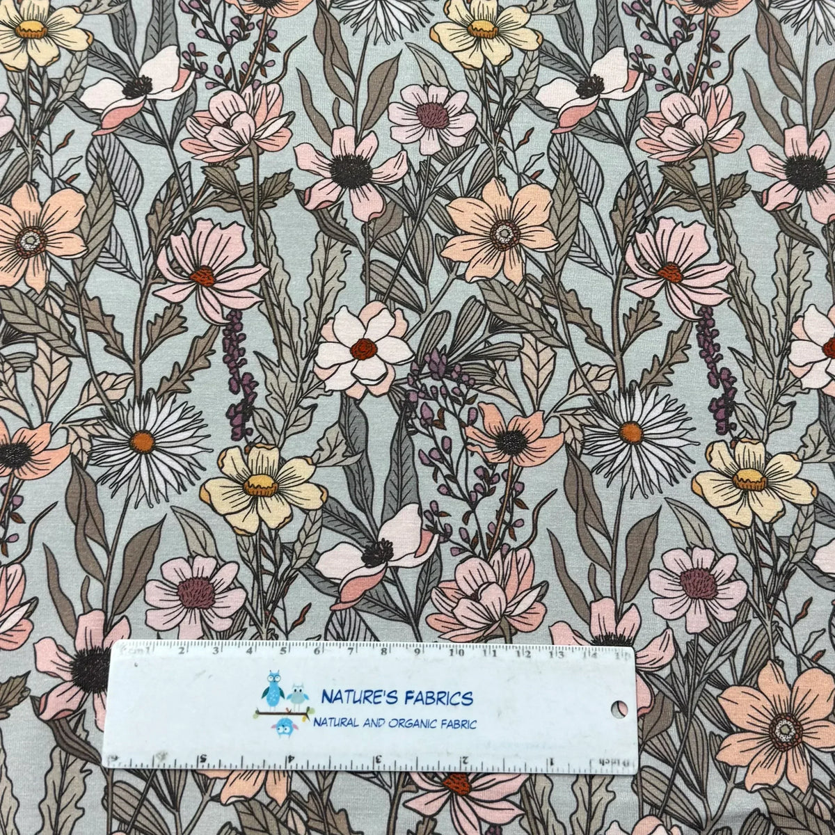 Nature's Fabrics floral print organic cotton fabric with pink, white, and yellow flowers on light blue background