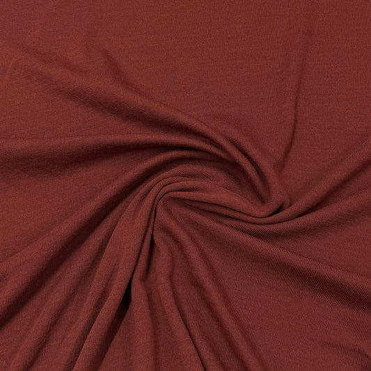 Rich rust-colored organic cotton knit fabric by Nature's Fabrics, soft texture with gentle swirl folds