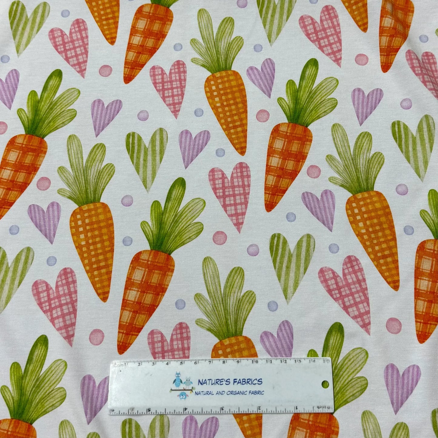 Carrot and heart patterned organic cotton fabric by Nature's Fabrics, featuring plaid carrots, colorful hearts, and polka dots on white background.