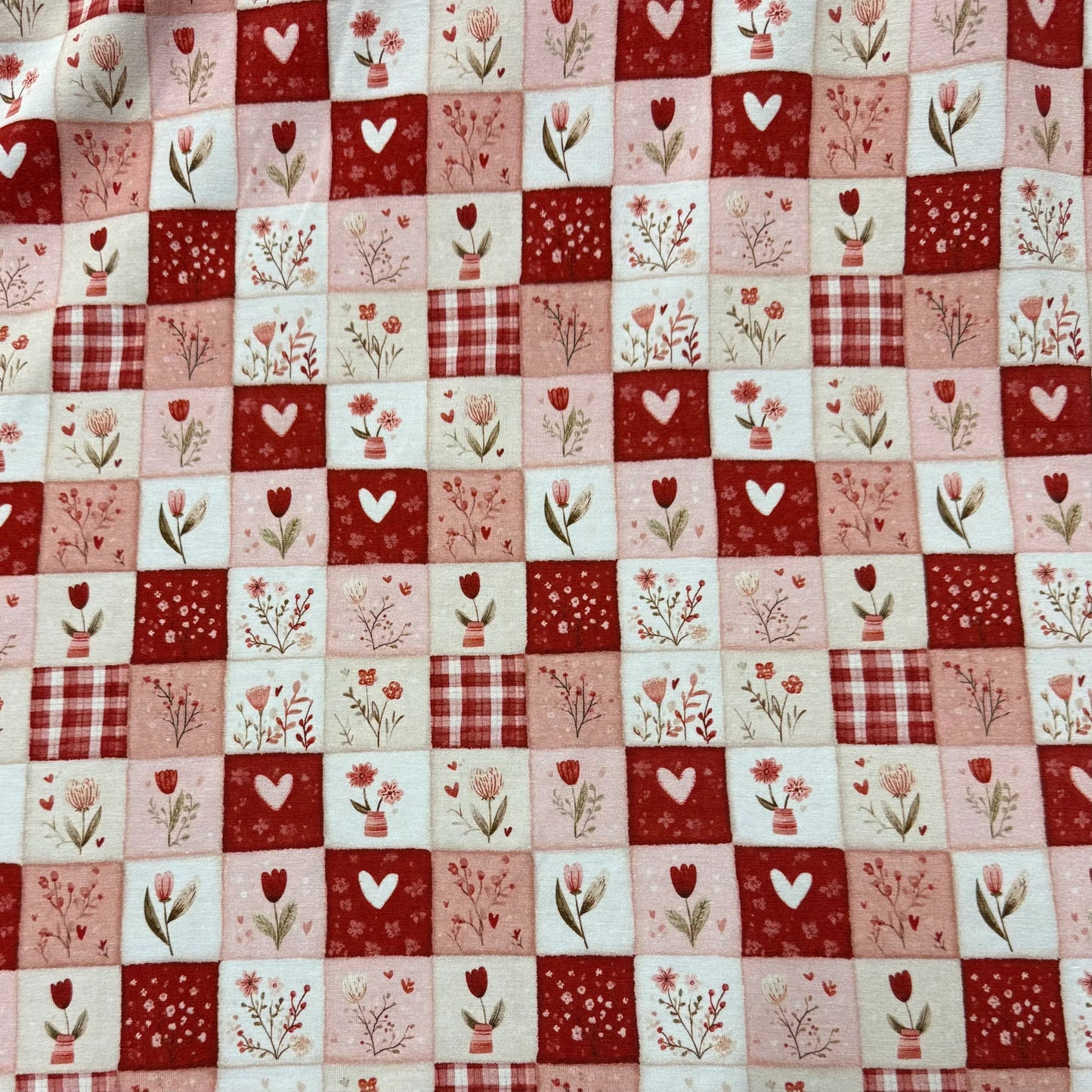 Red and pink patchwork fabric with hearts, tulips, and plaid by Nature's Fabrics