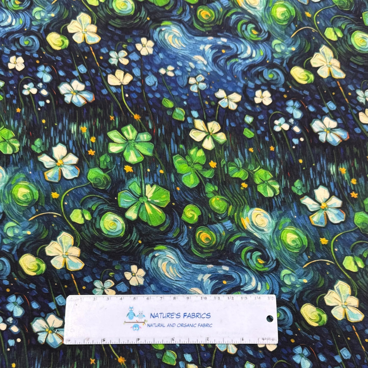 Nature's Fabrics Van Gogh-style floral print fabric with swirling blue and green patterns, featuring white flowers and clovers, measured with a ruler.