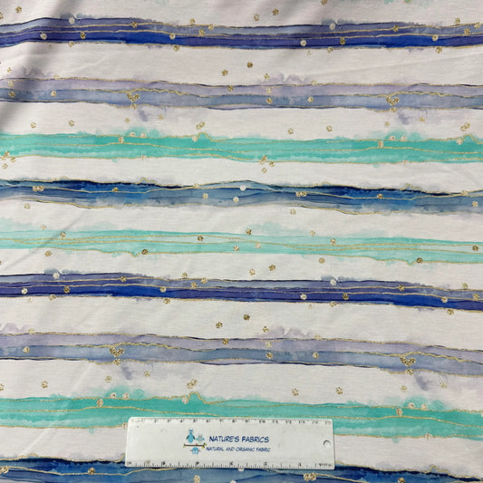Nature's Fabrics organic fabric featuring blue and teal watercolor stripes with gold speckles.