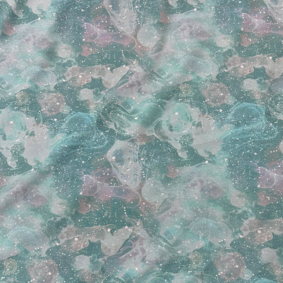Nature's Fabrics teal and blue marbled abstract print fabric with white speckles.