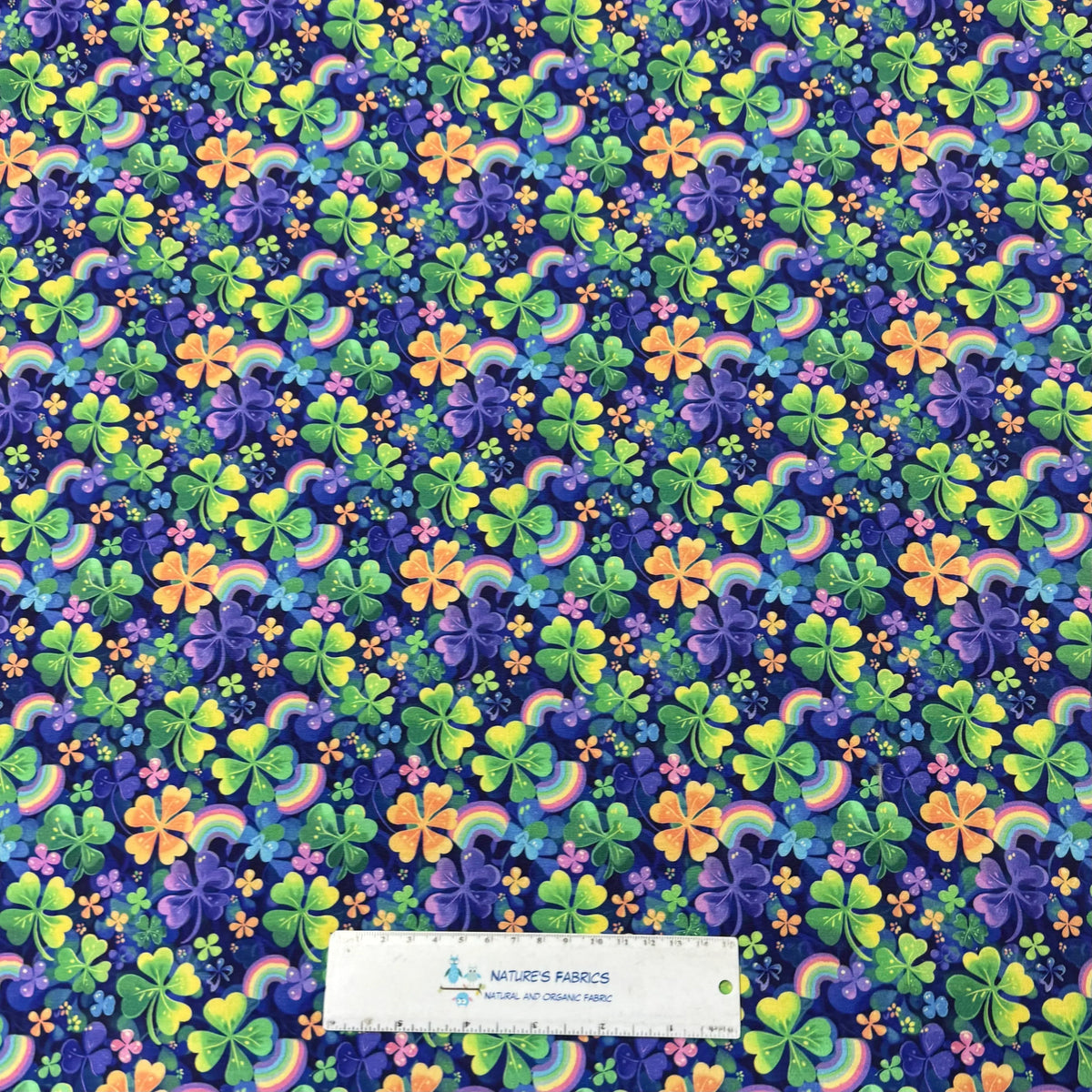 Nature's Fabrics rainbow shamrock print fabric with green, purple, orange clovers and rainbows on navy background