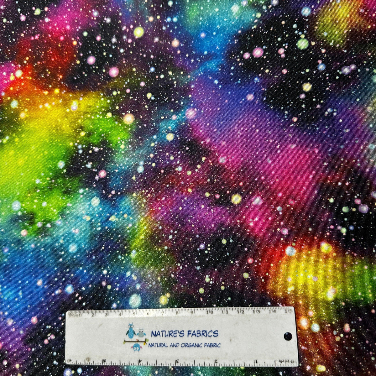 Colorful galaxy print organic fabric from Nature's Fabrics with a measurement ruler.