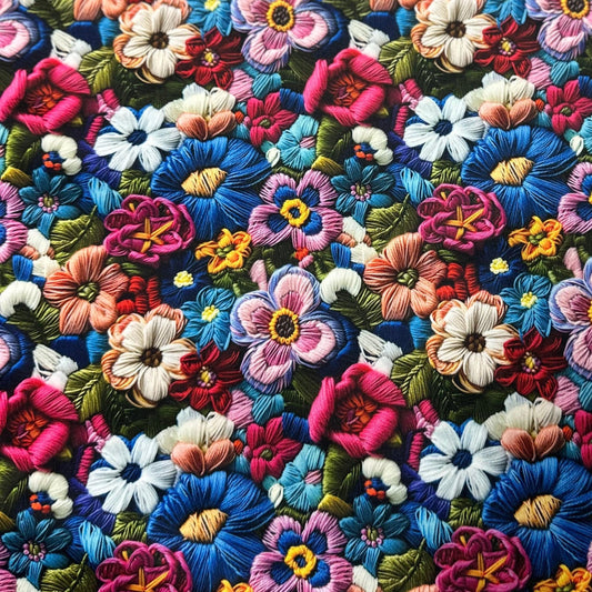 Colorful floral embroidery fabric from Nature's Fabrics featuring vibrant stitched flowers.