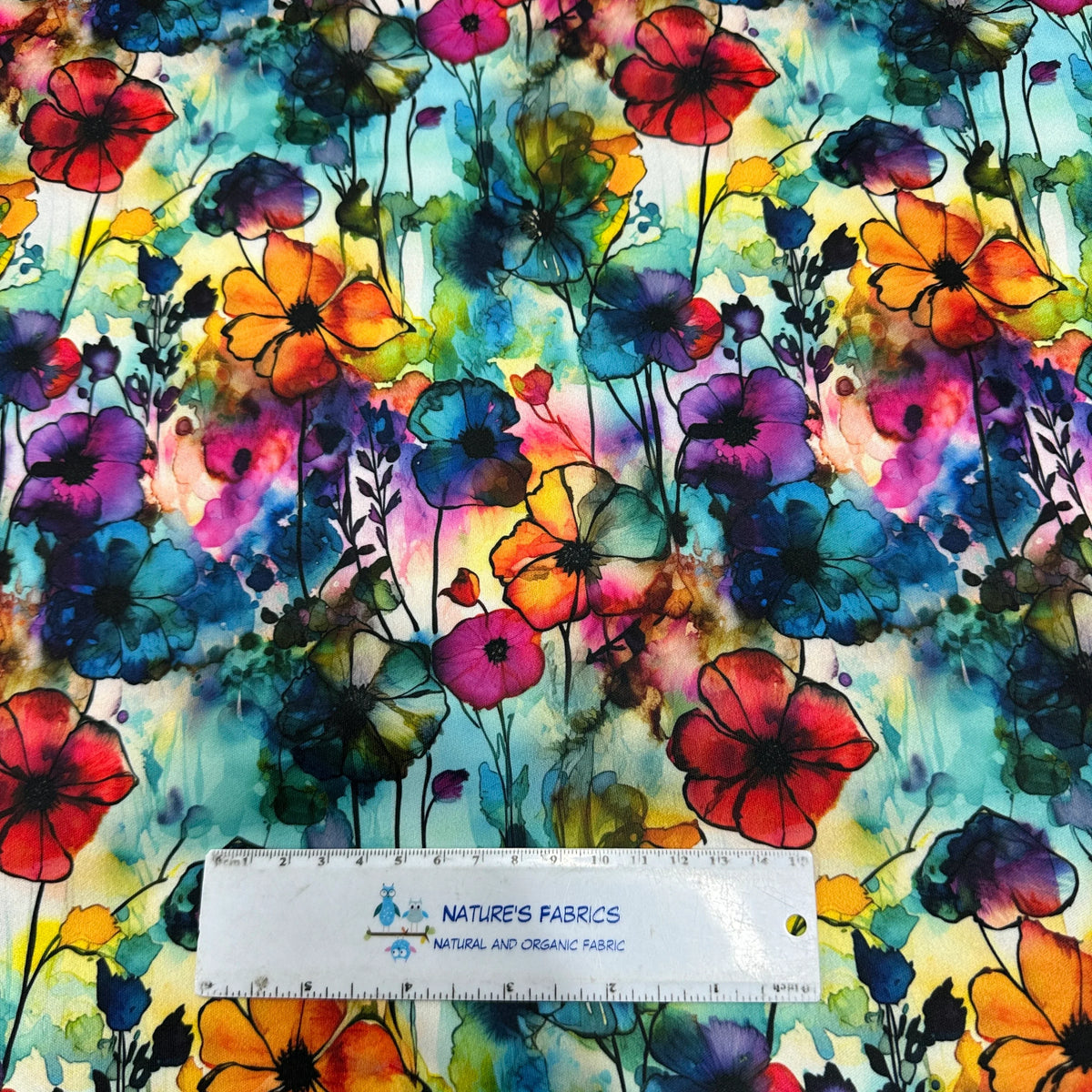 Nature's Fabrics colorful watercolor floral print organic fabric with a ruler for scale.