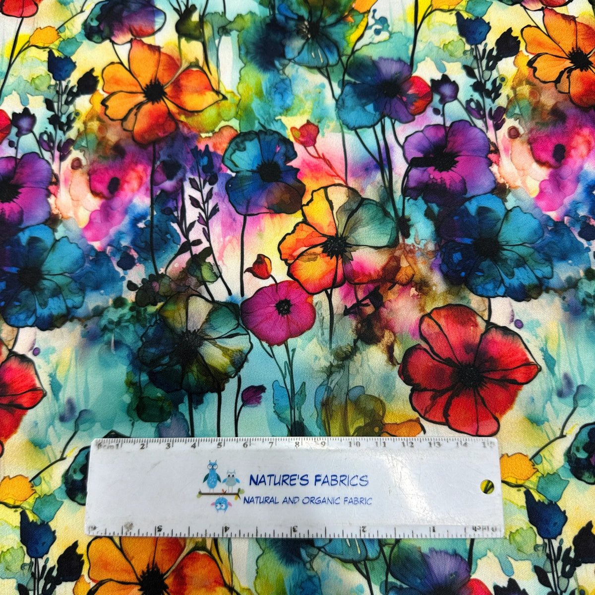 Colorful watercolor floral print organic fabric from Nature's Fabrics with a measuring ruler.