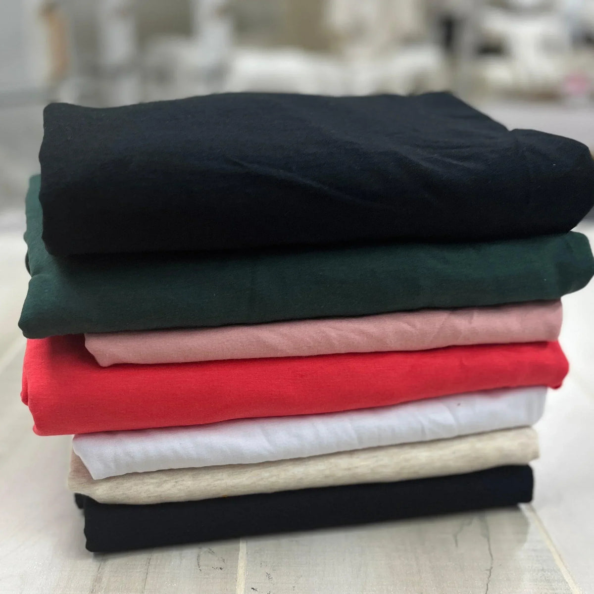 A stack of Nature's Fabrics premium natural fabric bolts in various colors.