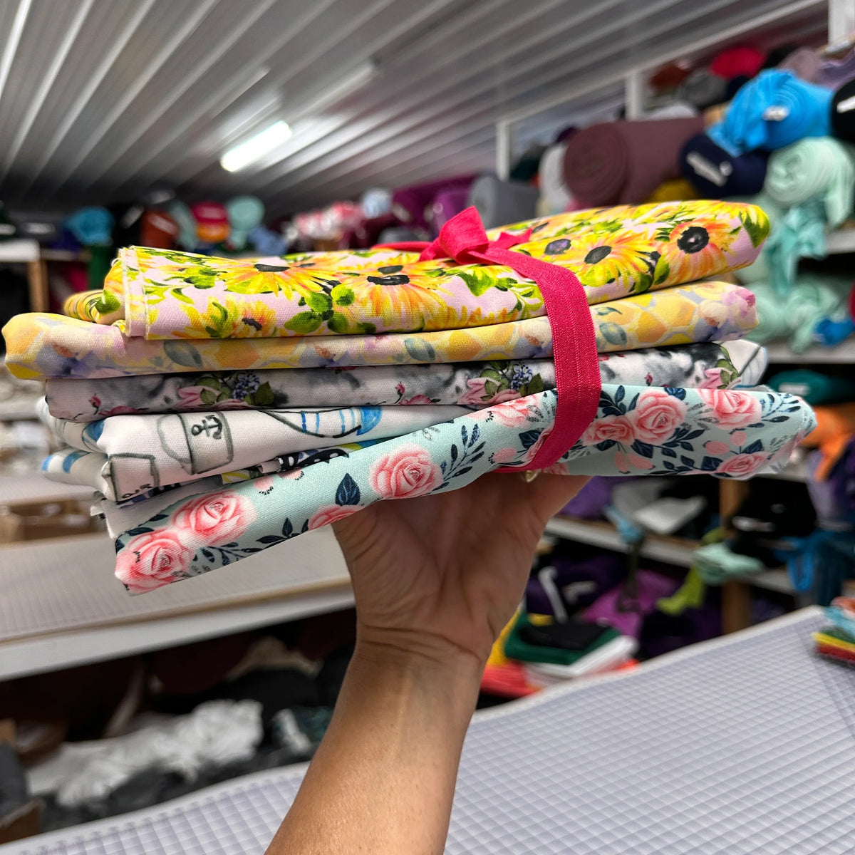 A stack of floral printed organic cotton fabrics from Nature's Fabrics tied with a pink ribbon.