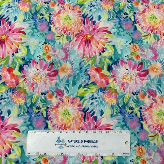Nature's Fabrics watercolor floral print fabric in pink, blue, and green with a ruler for scale.