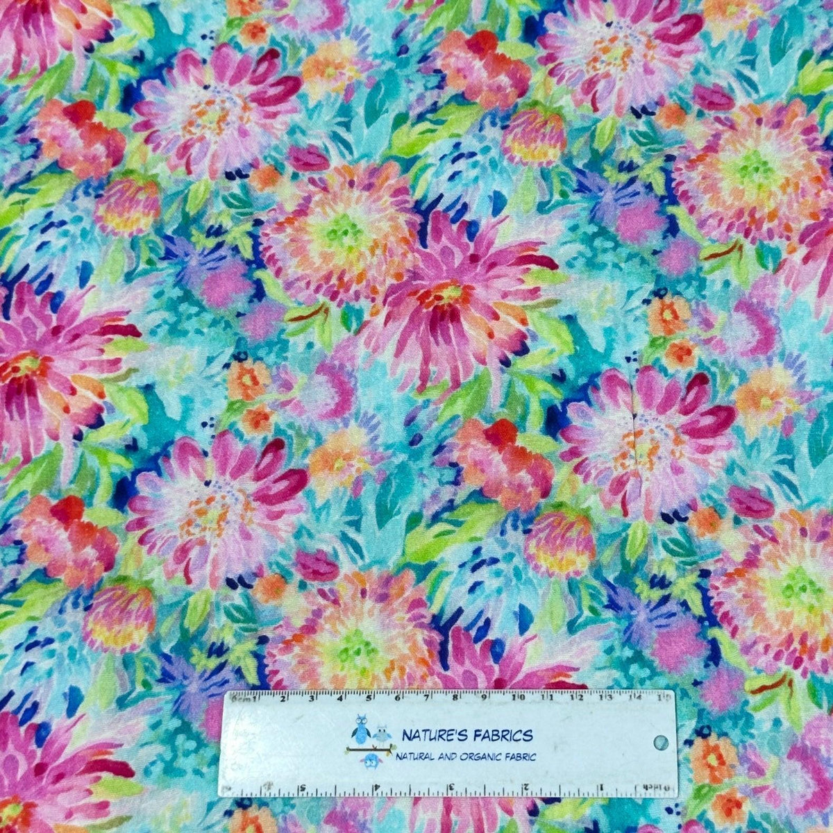 Nature's Fabrics colorful floral print organic fabric with a ruler for scale.