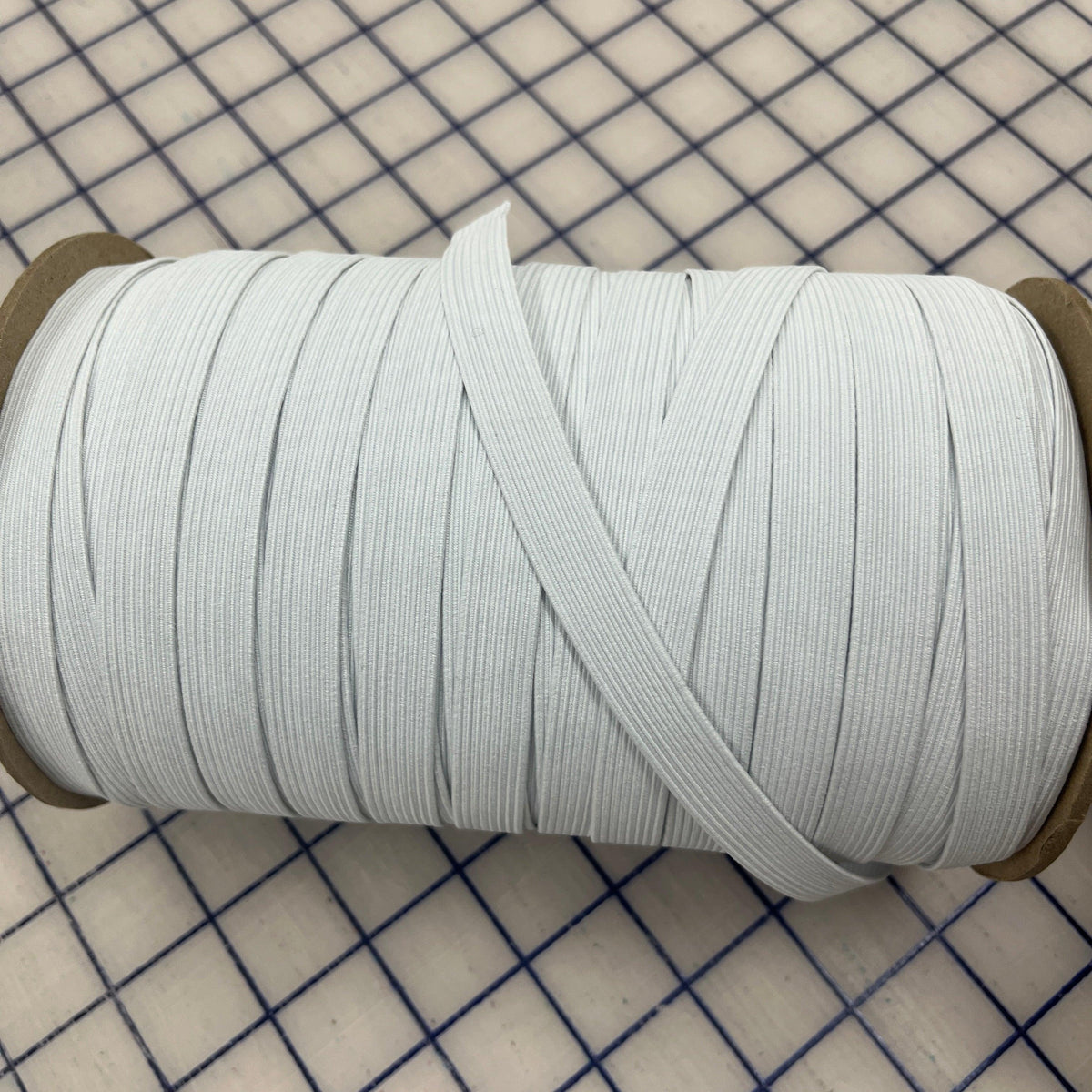 Roll of white elastic band from Nature's Fabrics on a gridded cutting mat