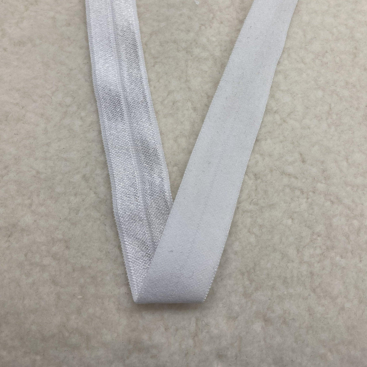 Close-up of white Nature's Fabrics elastic band on a textured white surface.