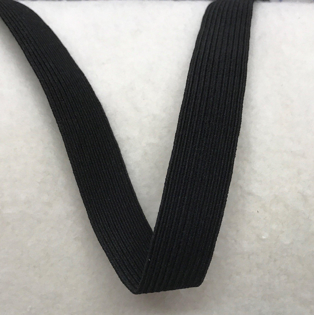 Nature's Fabrics black ribbed elastic band on a white textured background