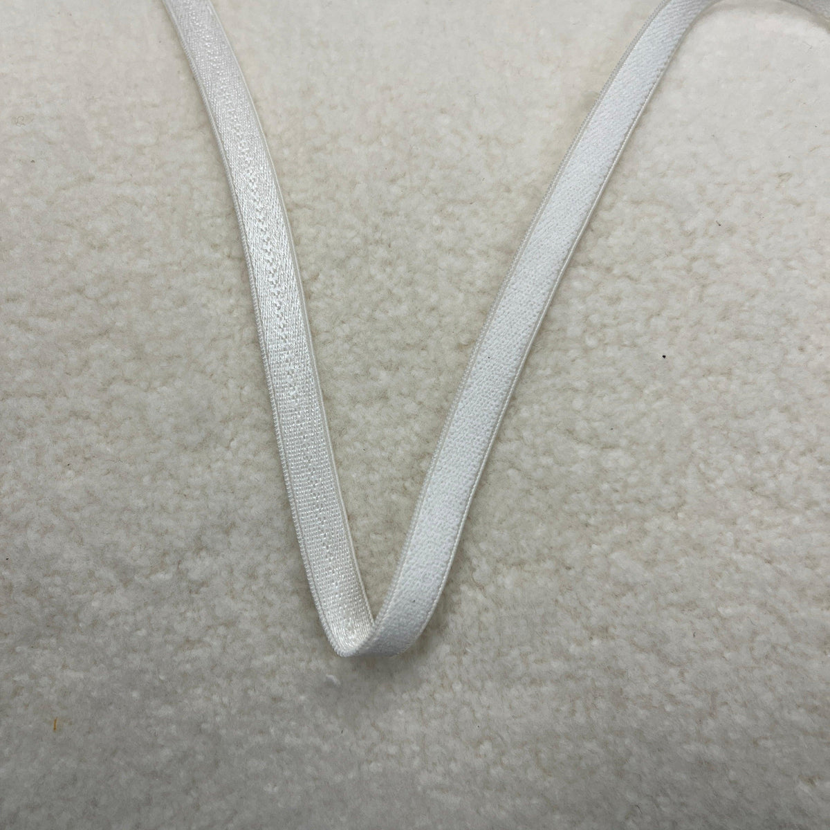 White Nature's Fabrics cotton ribbon on a white textured background