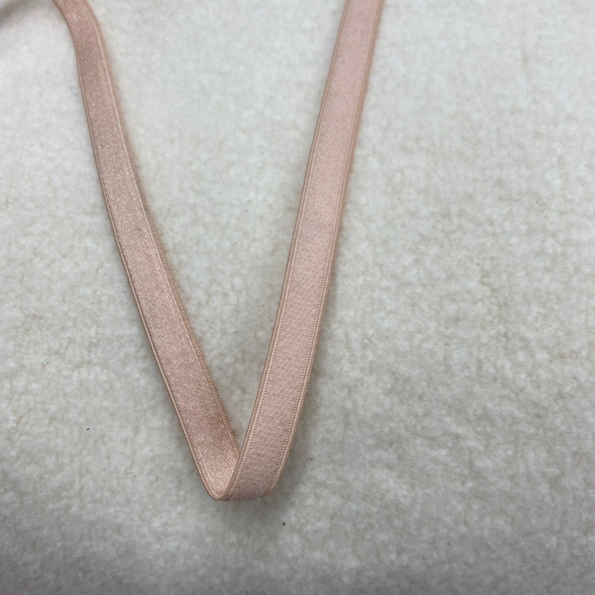 Nature's Fabrics light pink satin ribbon on a white textured background
