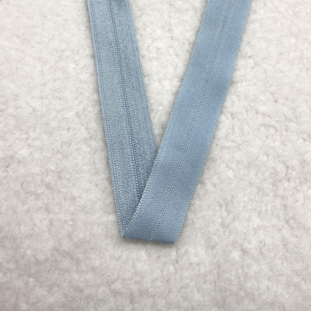 Light blue Nature's Fabrics elastic band on a white textured surface