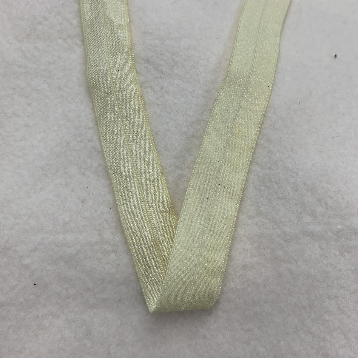 Pale yellow elastic band from Nature's Fabrics on a white textured background
