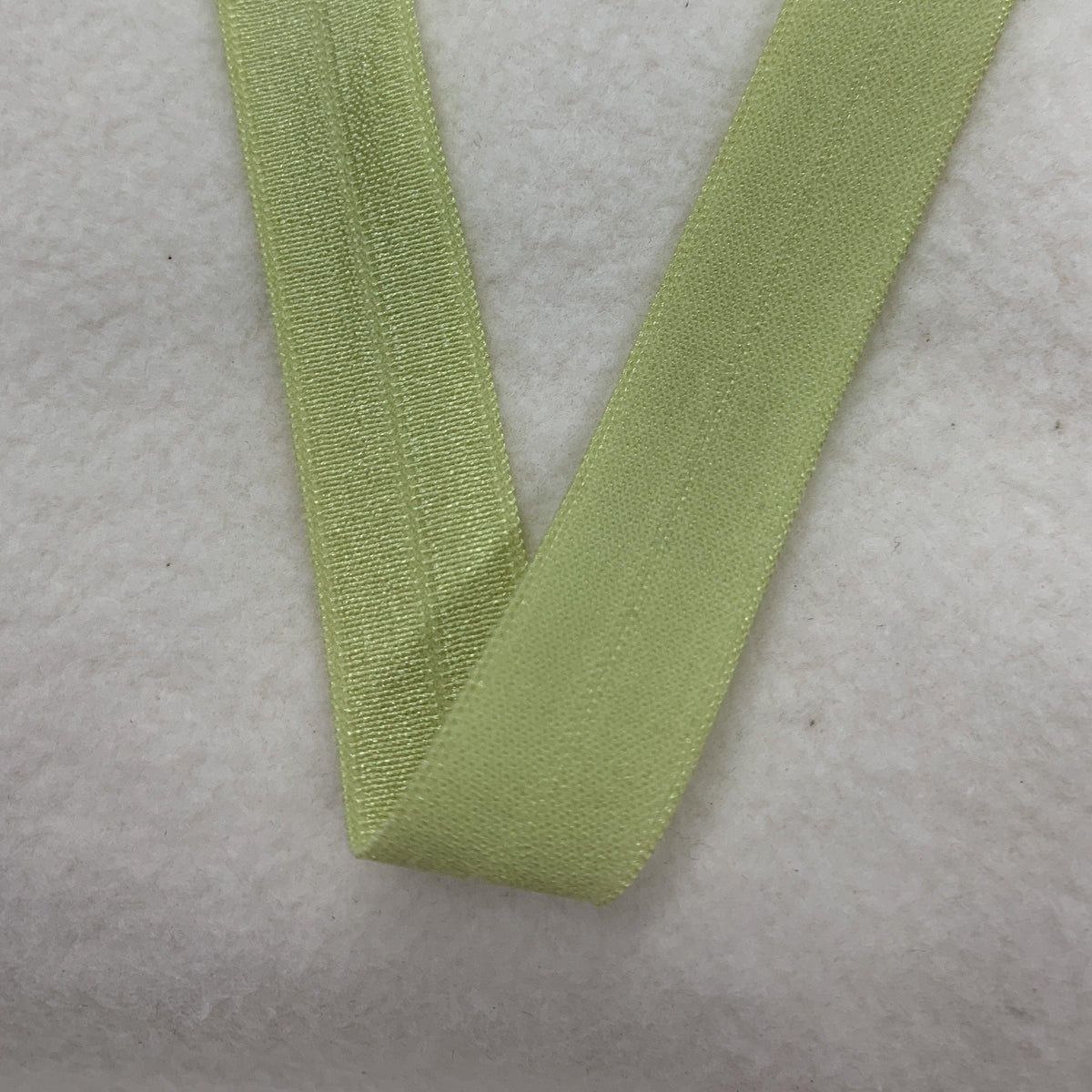 Light green elastic ribbon from Nature's Fabrics on a white textured surface