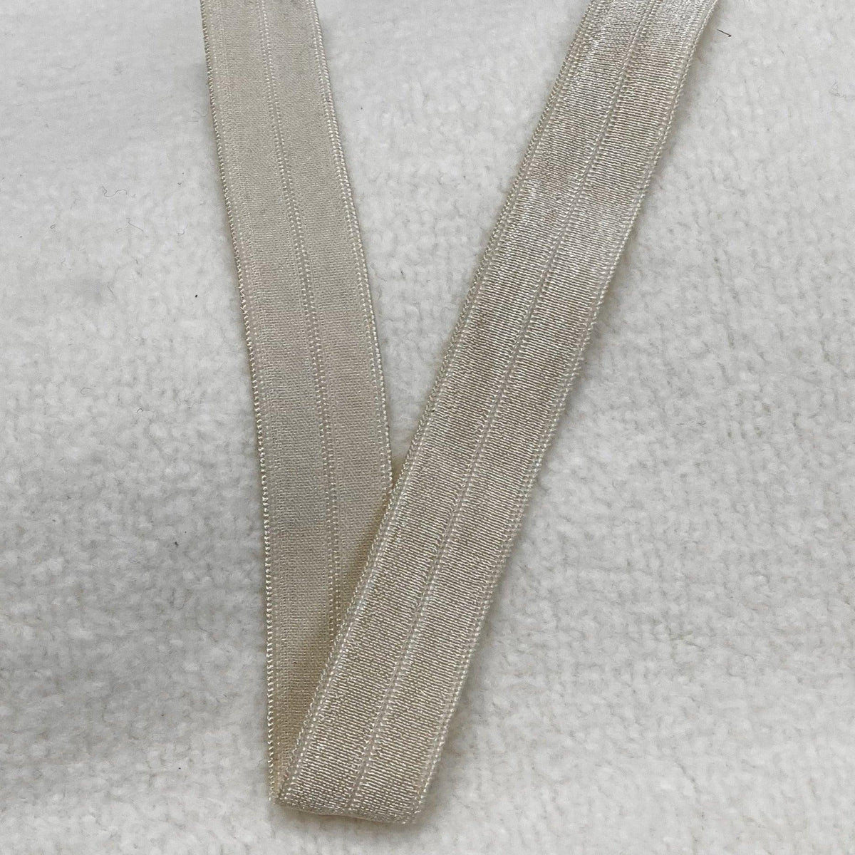 Off-white ribbed elastic trim from Nature's Fabrics on a white textured background.