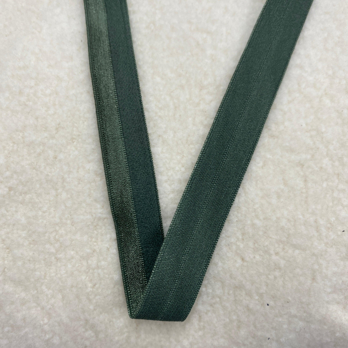 Nature's Fabrics dark green woven ribbon on a white textured background