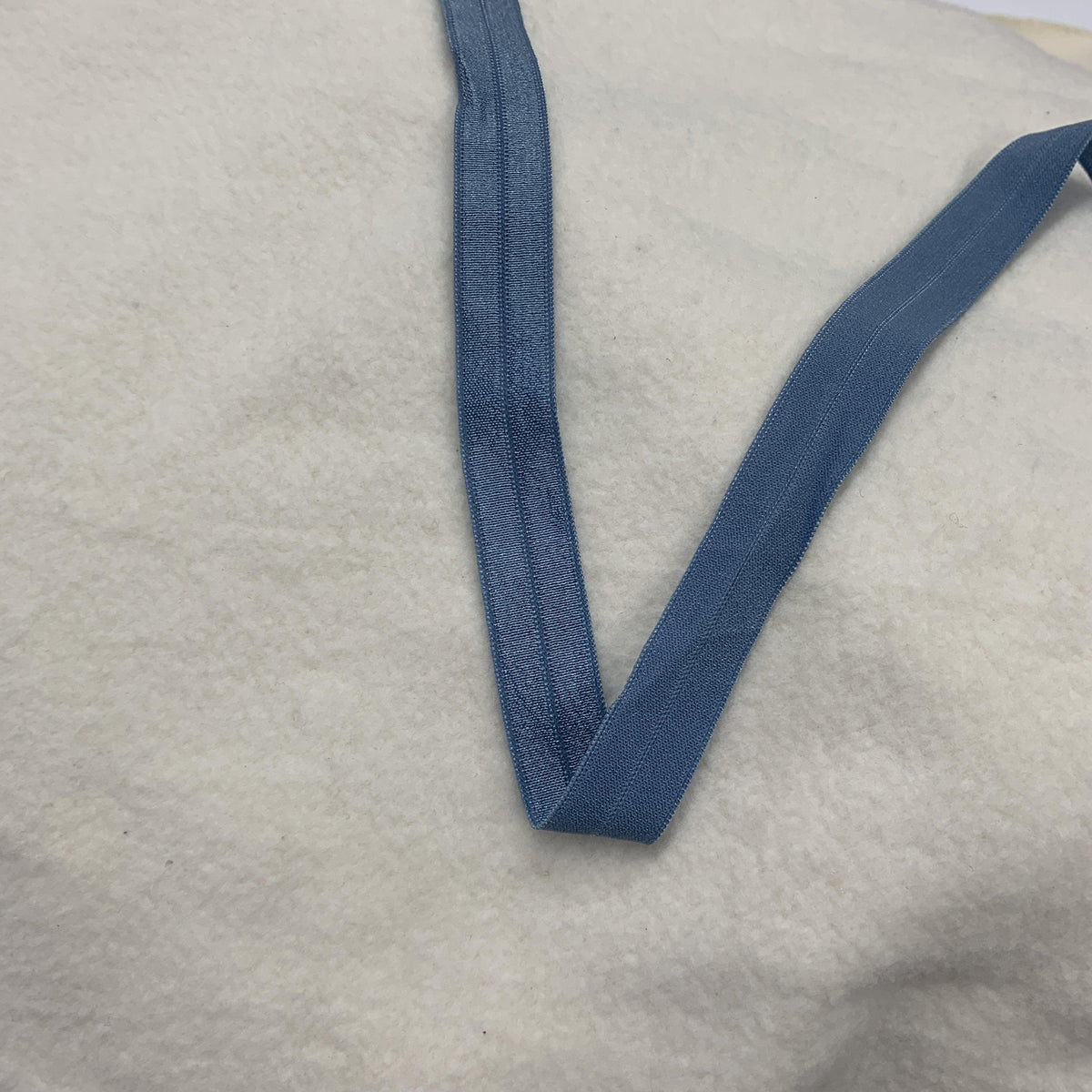 Nature's Fabrics blue elastic band on white textured fabric