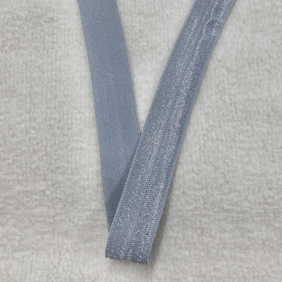 Nature's Fabrics silver elastic band on a white textured background