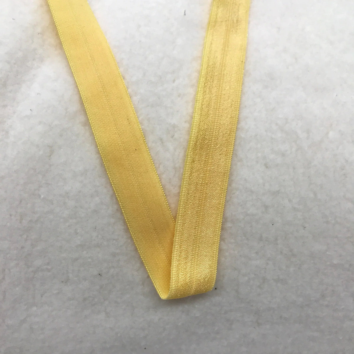 Yellow elastic band from Nature's Fabrics on a white textured background