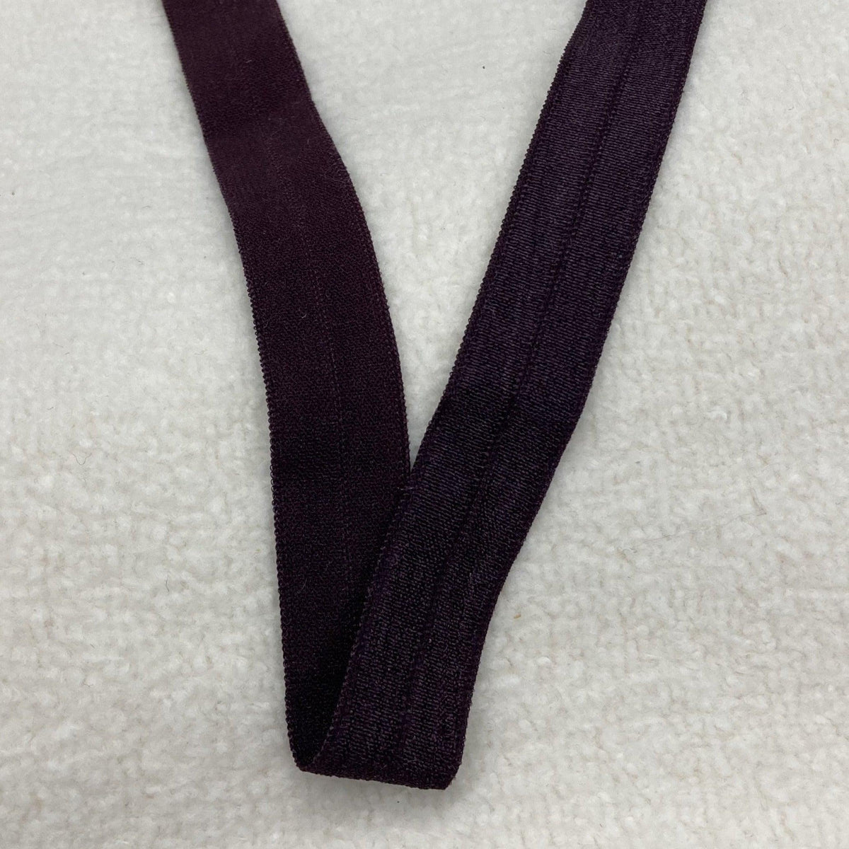 Nature's Fabrics deep purple elastic band on white textured background