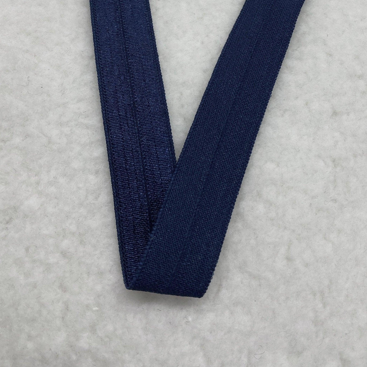 Navy blue elastic band from Nature's Fabrics on a white textured background