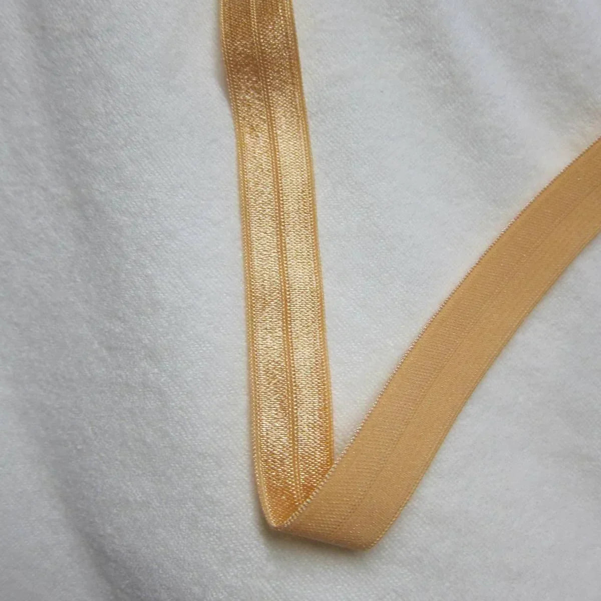 Nature's Fabrics gold elastic ribbon on a white textured fabric background