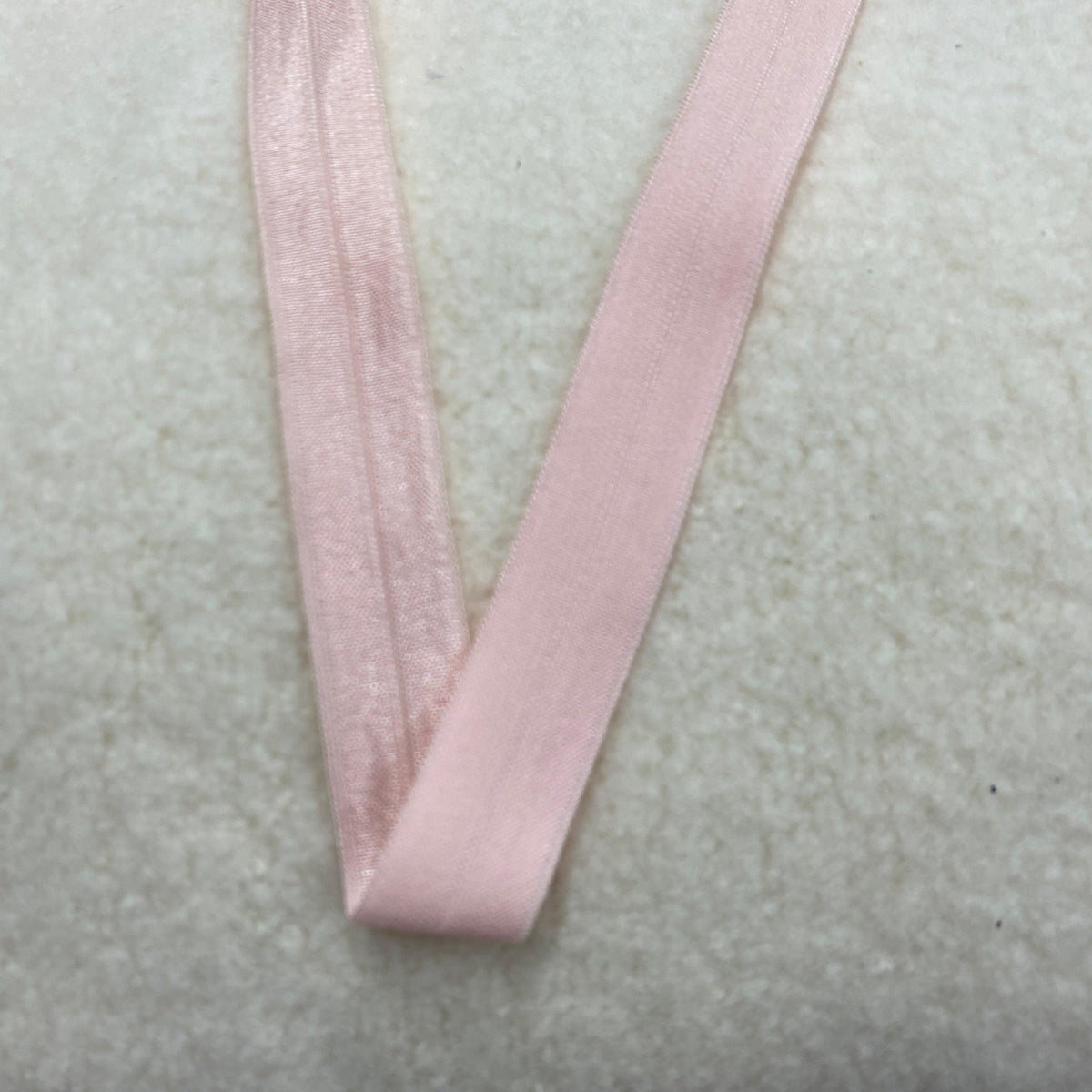 Light pink elastic band from Nature's Fabrics on a white textured surface