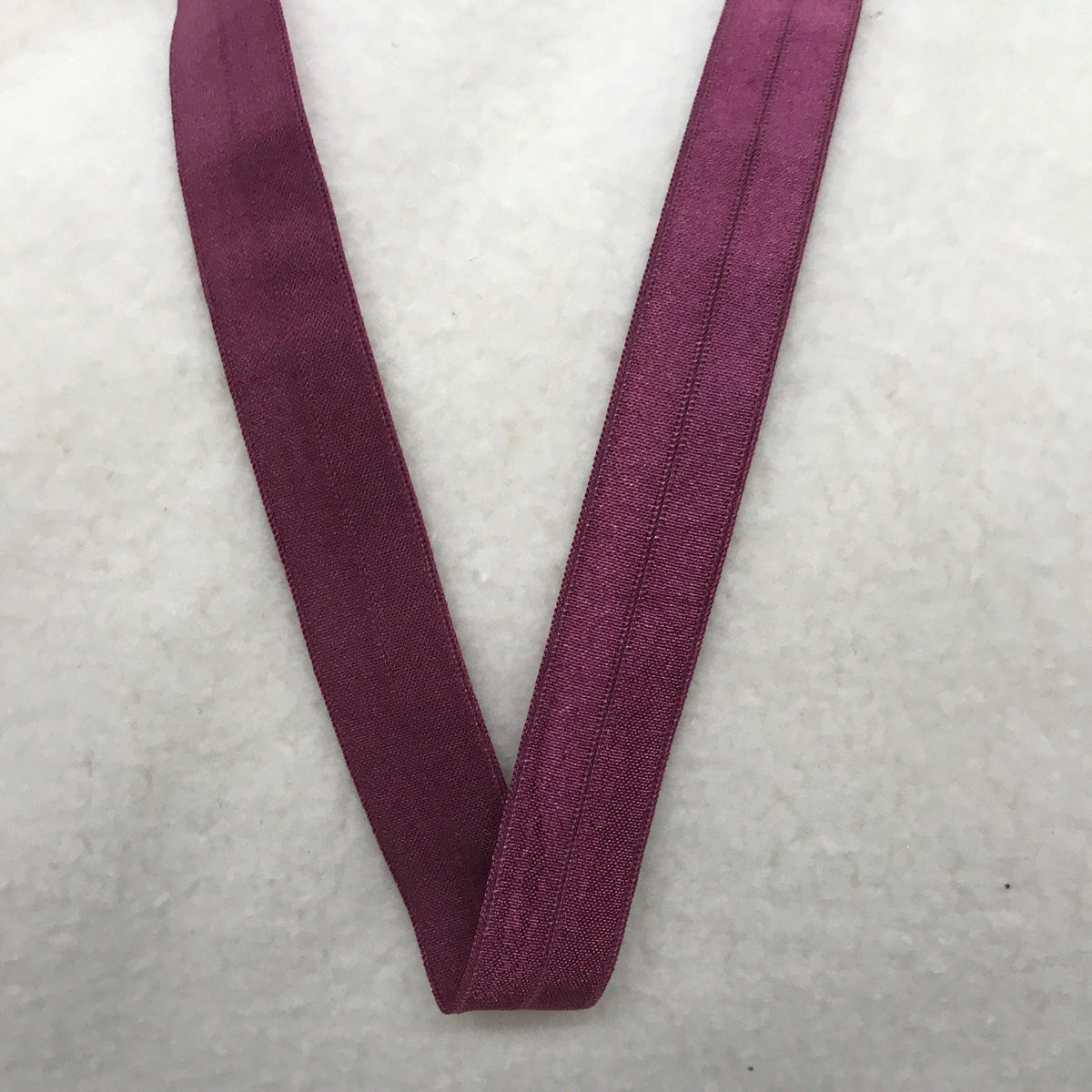 Nature's Fabrics purple elastic fabric band on a white textured background