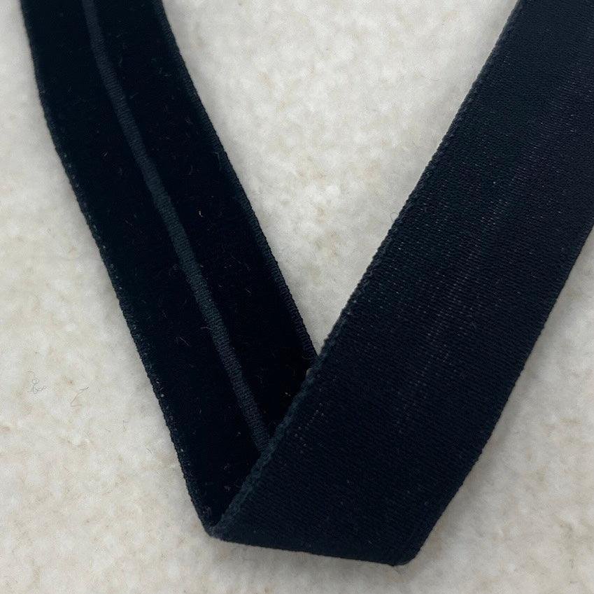 Close-up of black velvet ribbon from Nature's Fabrics on a white textured background.