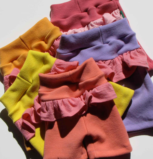 Assorted colorful Nature's Fabrics organic cotton baby bloomers in pink, yellow, and purple.