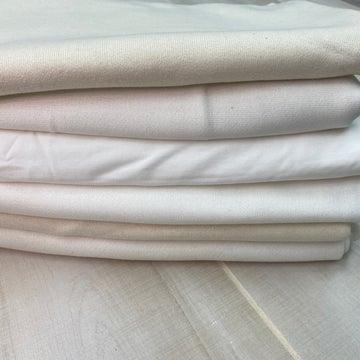 Stacked rolls of premium white natural fabric from Nature's Fabrics