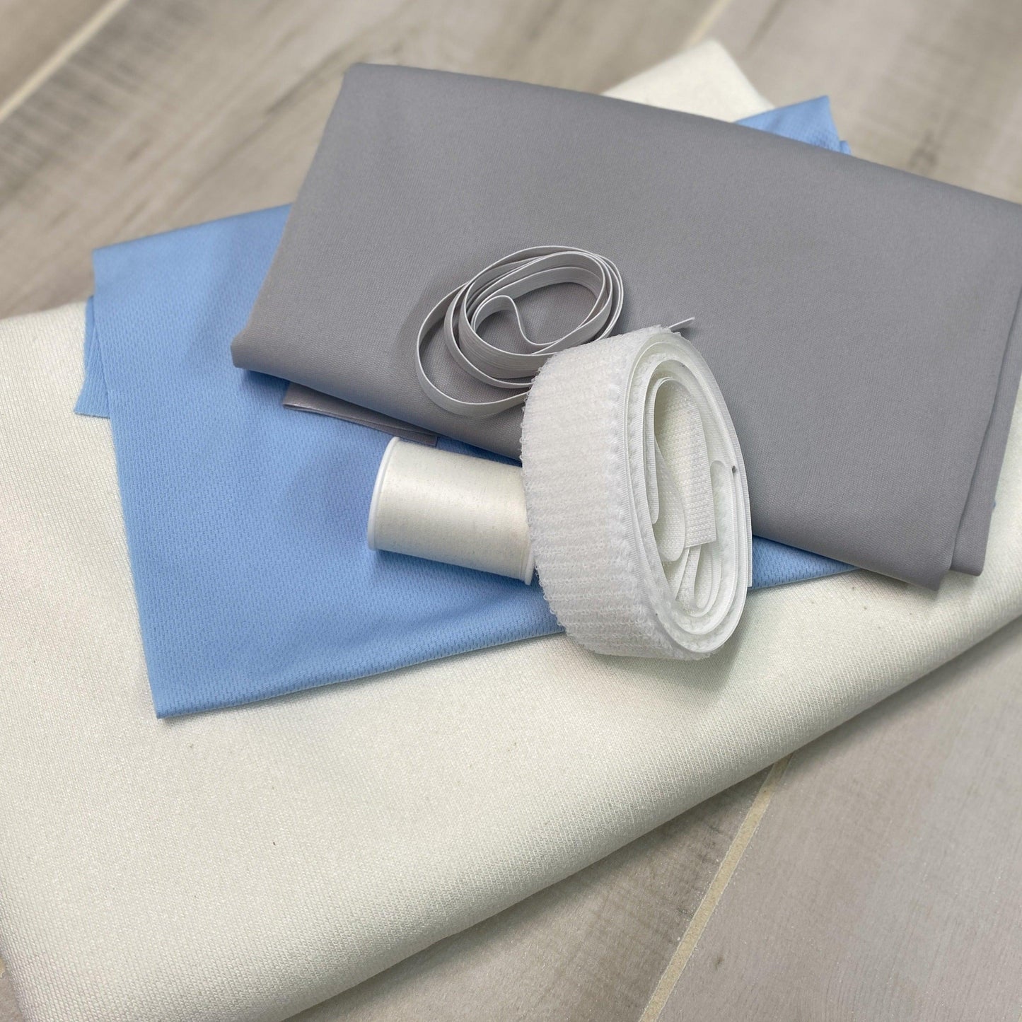 Nature's Fabrics premium fabric rolls in grey, blue, and white with matching elastic.