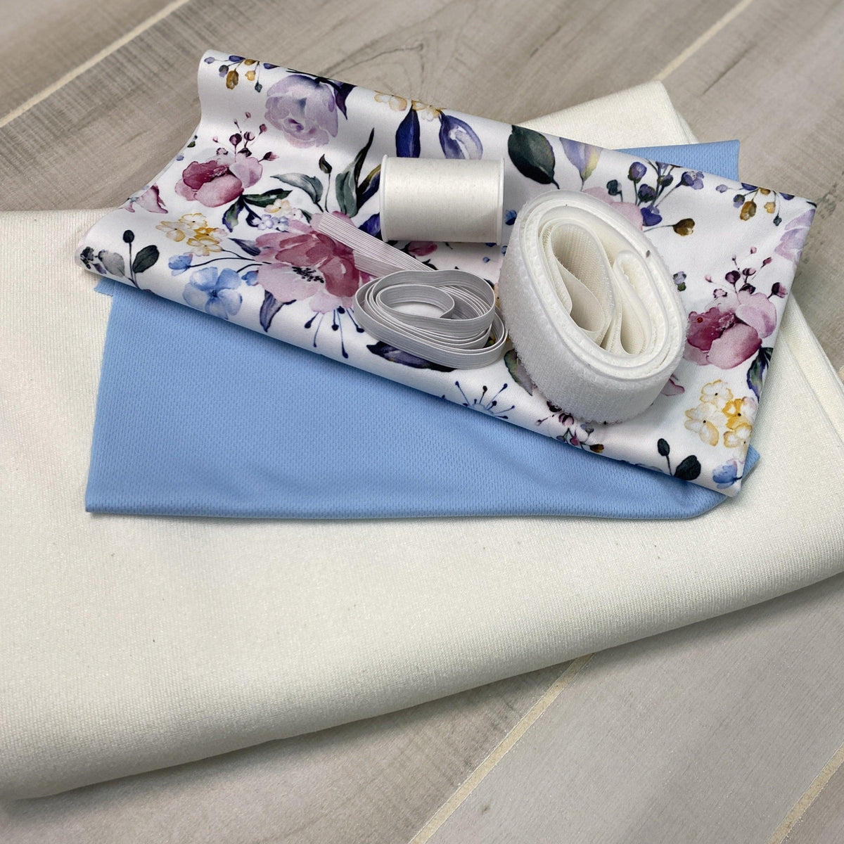 Nature's Fabrics floral and blue textile samples with white sewing notions.