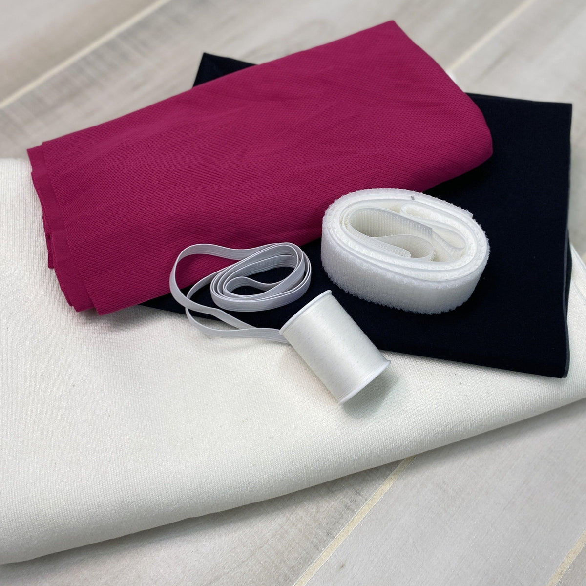 Nature's Fabrics collection of magenta, black, and white textiles with sewing notions.